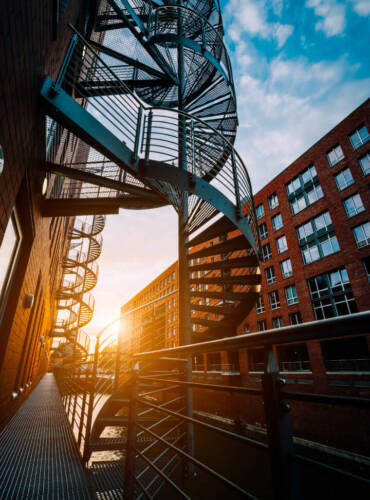 Winding stairs in the old Warehouse District. Narrow canal and red brick buildings of Speicherstadt in Hamburg in the warm sunset light. low angle shot.